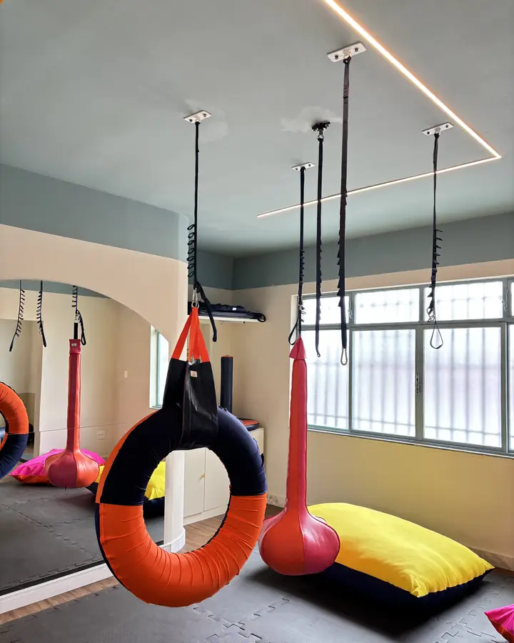 Sala de integração sensorial com balanços, pneu suspenso e almofadas
