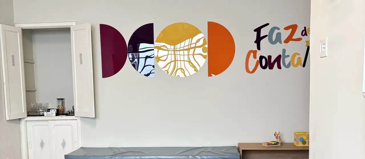 Recepção da clínica com sofá claro e o logotipo colorido na parede