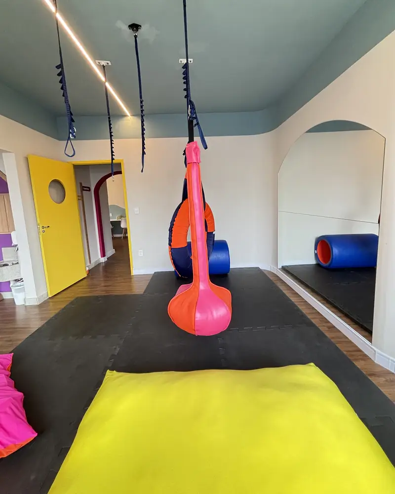 Sala com equipamentos suspensos e almofadas coloridas